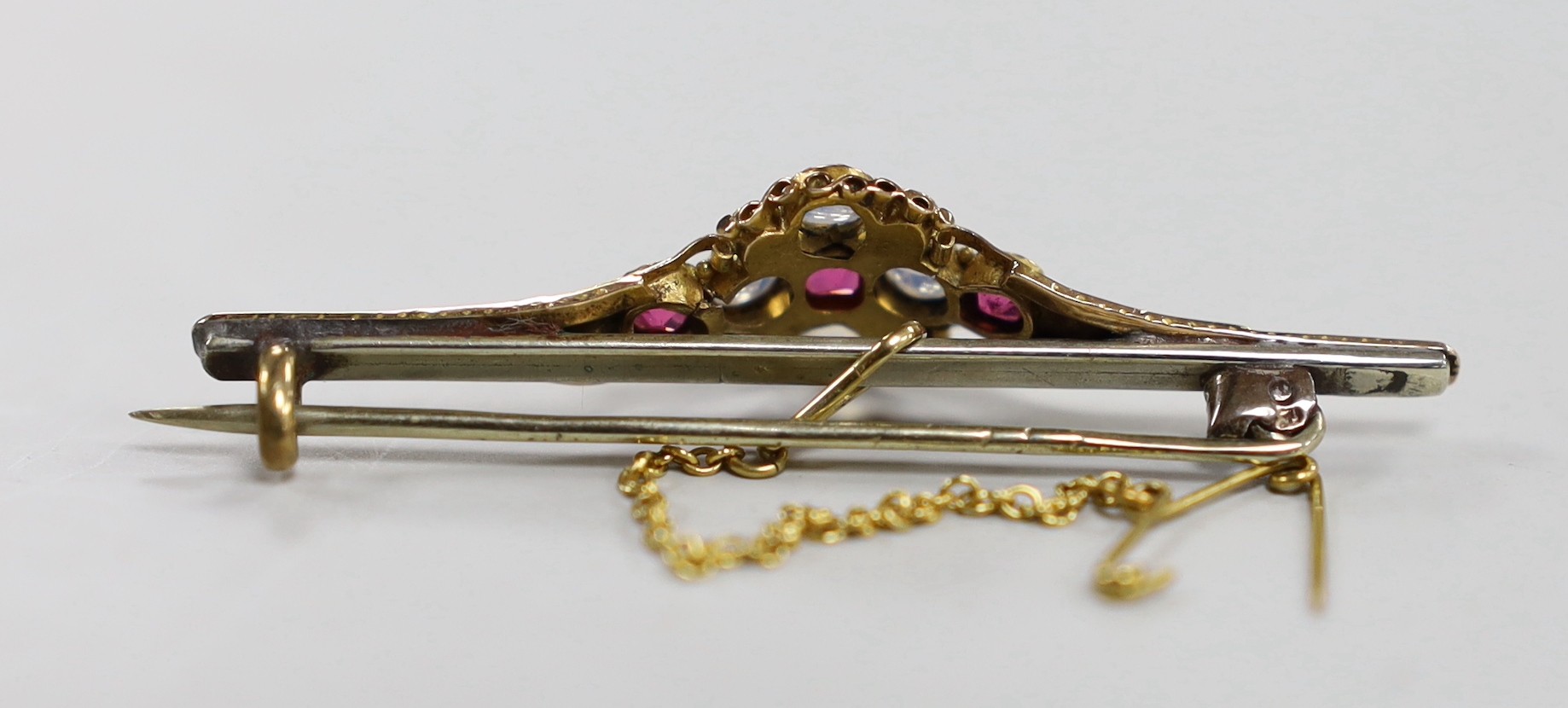 An early 20th century, yellow metal, moonstone, ruby and green garnet cluster set bar brooch, 51mm, with later pin attachment?, gross weight 4.1 grams.